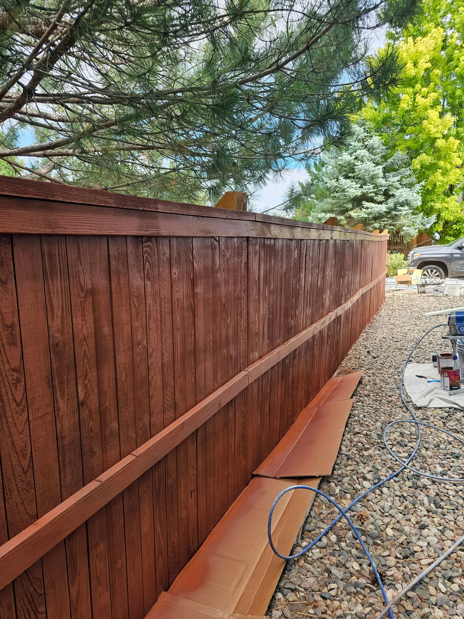 Fence being stained with paper protecting the gravel below