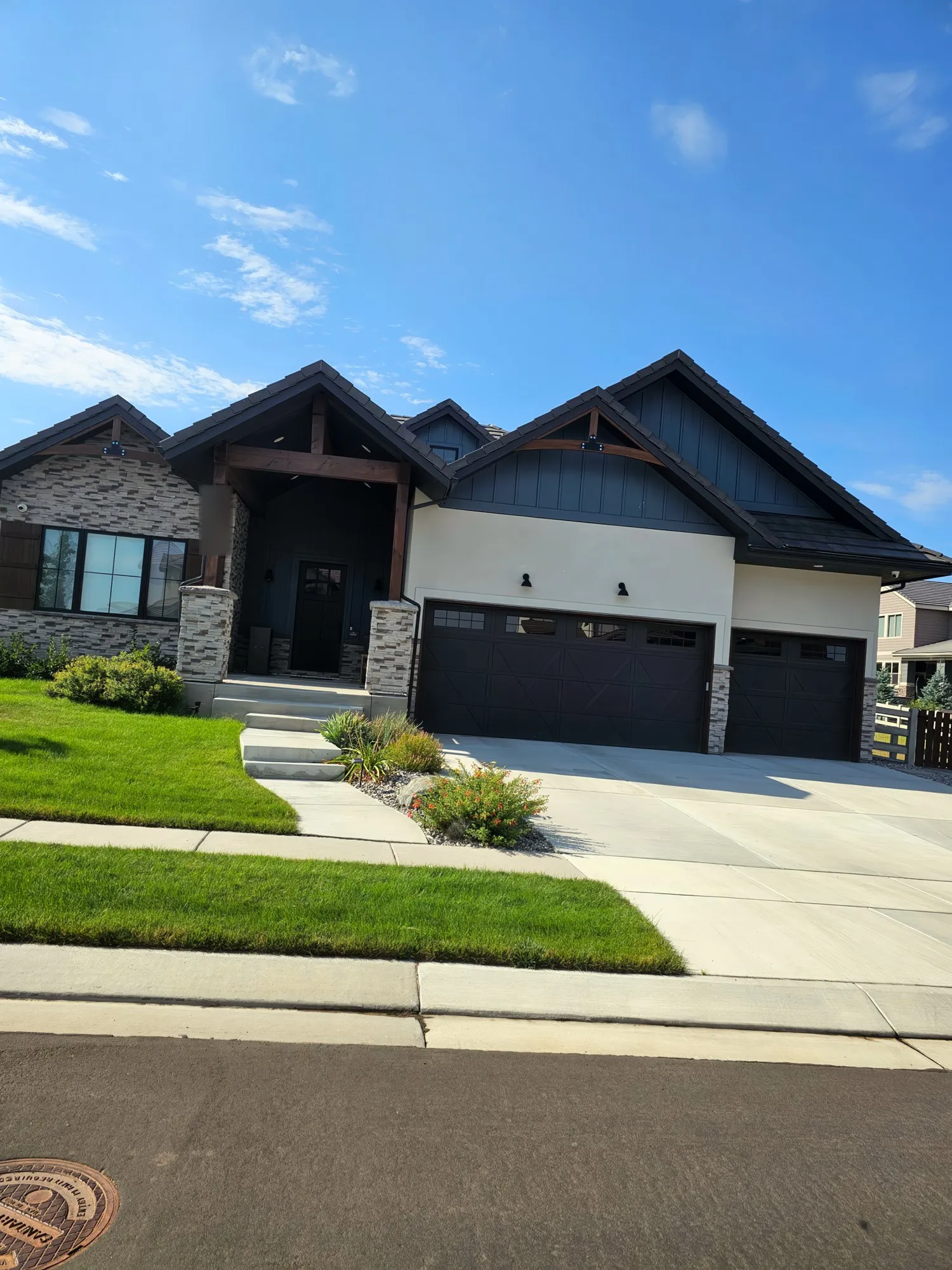Modern farmhouse with white stucco, dark trim and stone columns