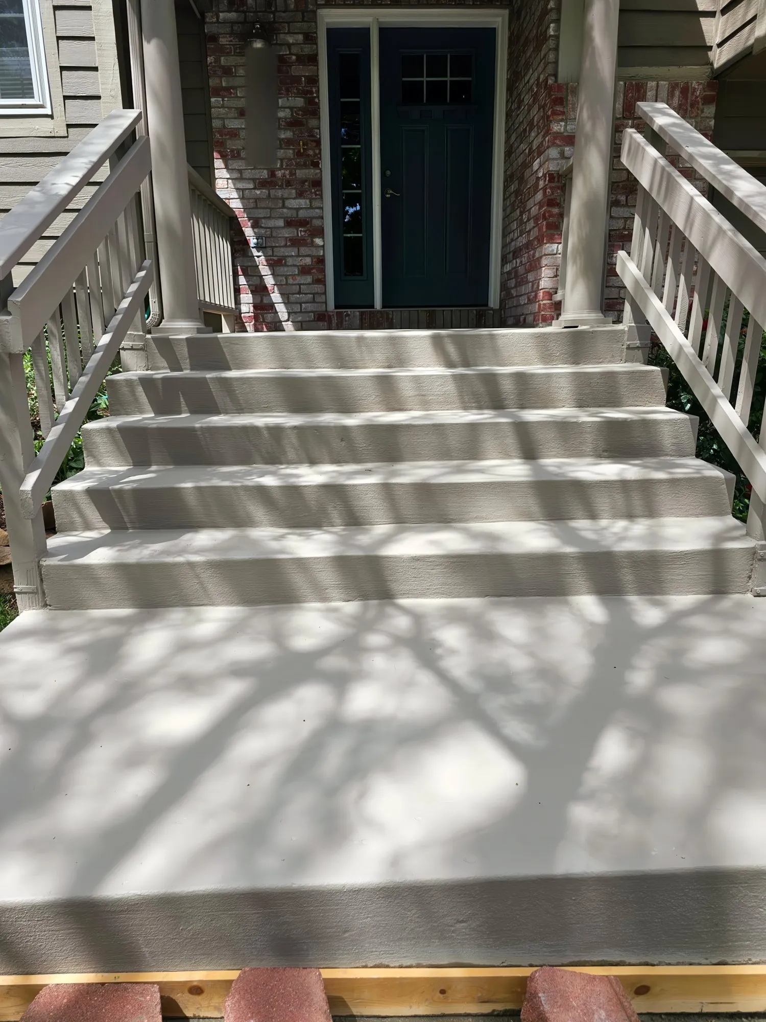 Freshly coated front porch and steps leading to a green door