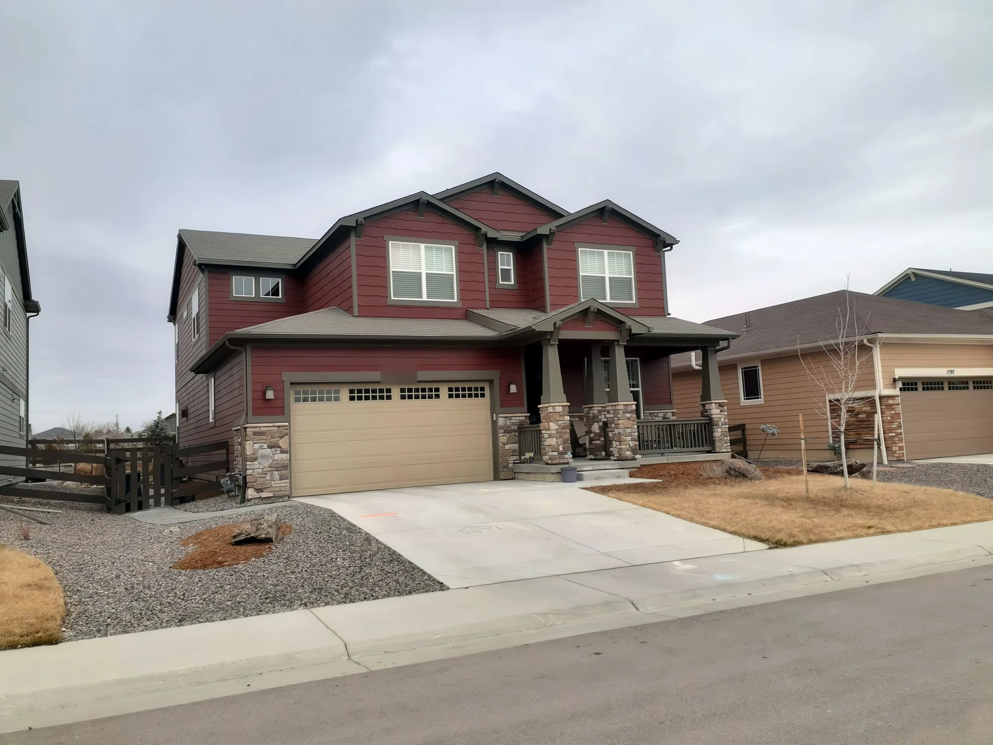 Red two-story house with stone columns and a front porch