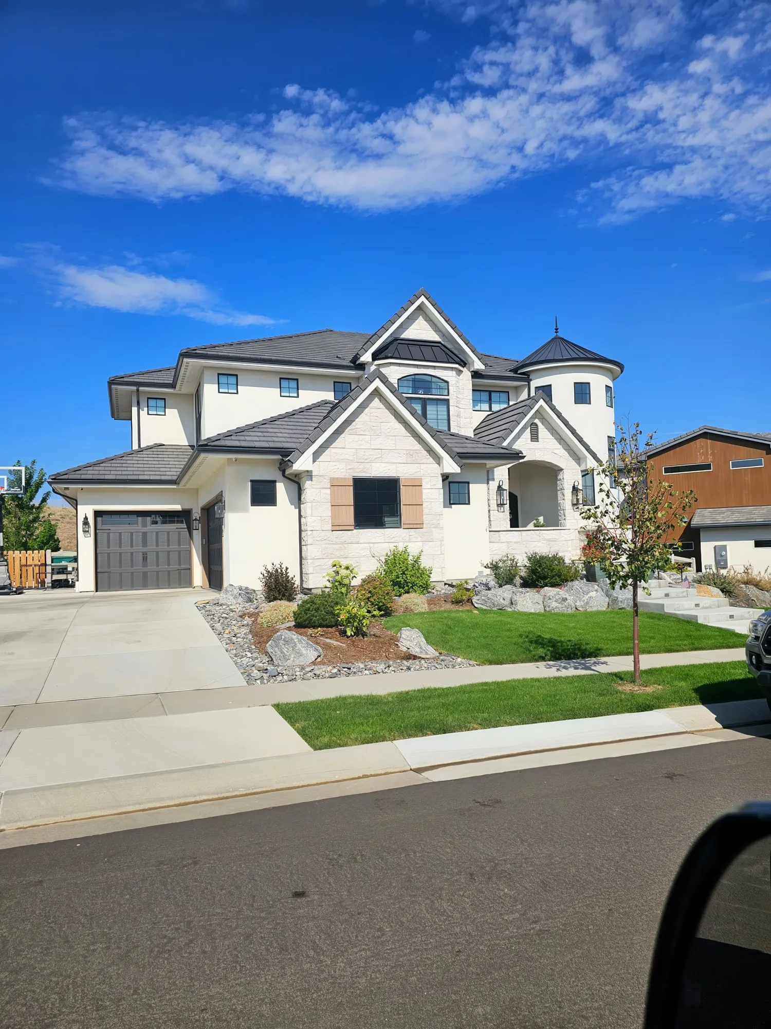 Large white custom home with gray roof under a blue sky